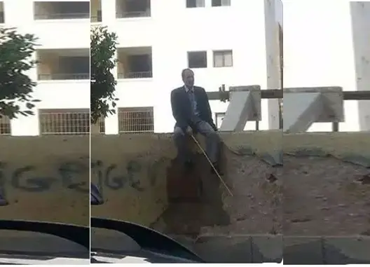 مدير مدرسة يجلس على سورها حاملا عصا لمنع التلاميذ من الهروب (صورة)