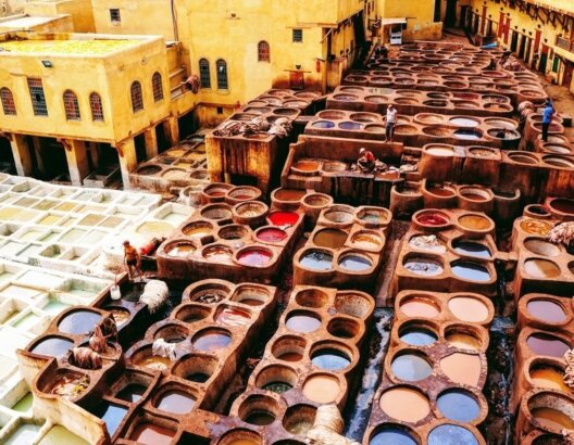 ورش دباغة تقليدية في مبنى قديم بحفر ملونة وسوائل جلدية وصناع يعملون
