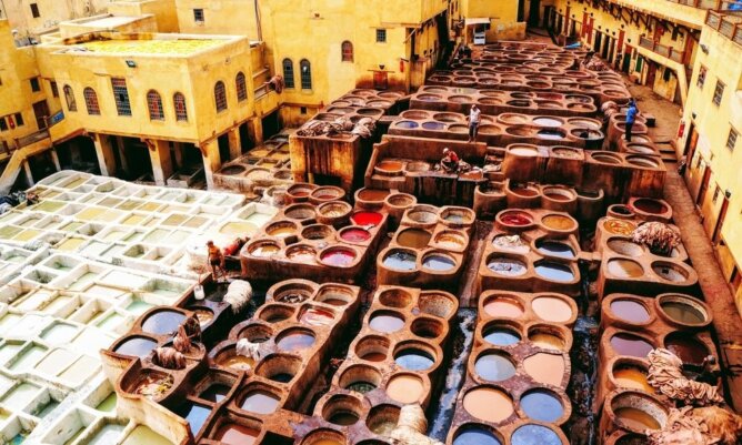ورش دباغة تقليدية في مبنى قديم بحفر ملونة وسوائل جلدية وصناع يعملون