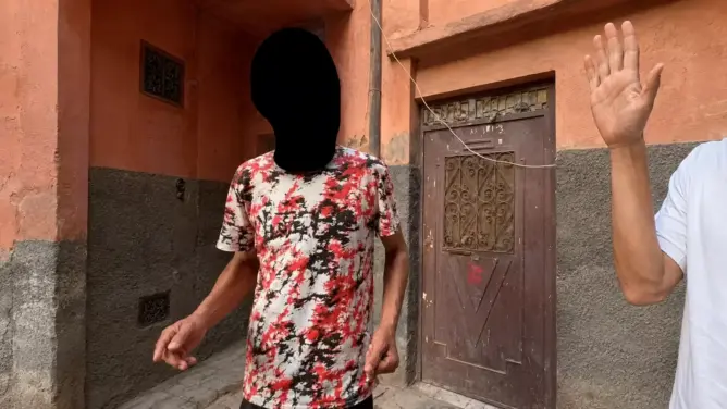 شخصان في زقاق ضيق بمراكش قرب باب خشبي قديم خلال خلاف