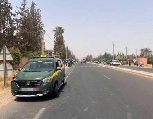 طريق حضري واسع مع سيارة أجرة خضراء وسوداء وأشجار نخيل في مراكش