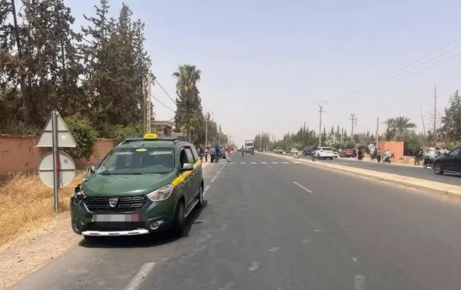 طريق حضري واسع مع سيارة أجرة خضراء وسوداء وأشجار نخيل في مراكش