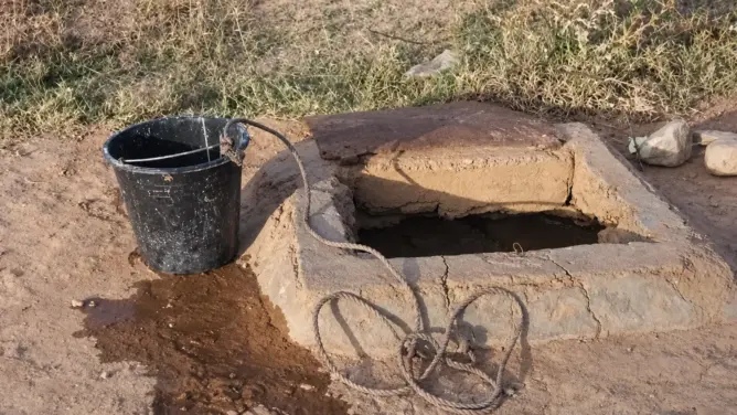 بئر مائي تقليدي بحبل ودلو في منطقة جافة تعبير عن مخاطر المطفيات