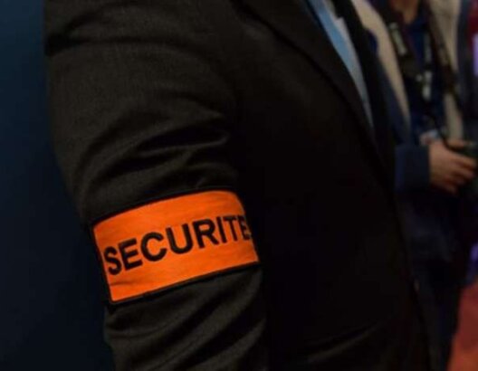 شريط أمن برتقالي مكتوب عليه SECURITE على ذراع شخص بخلفية غير واضحة