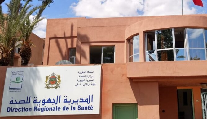 مبنى المديرية الجهوية للصحة باللافتة الرسمية وعلم أحمر وأشجار نخيل