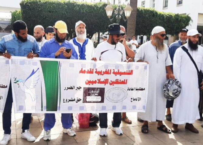 مجموعة رجال يحملون لافتة تضامن عربي لإغاثة زلزال سوريا وتركيا في ساحة عامة