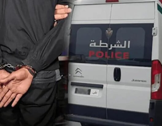 شخص مقيد أمام سيارة شرطة تحمل شعار الشرطة في عملية أمنية بمراكش